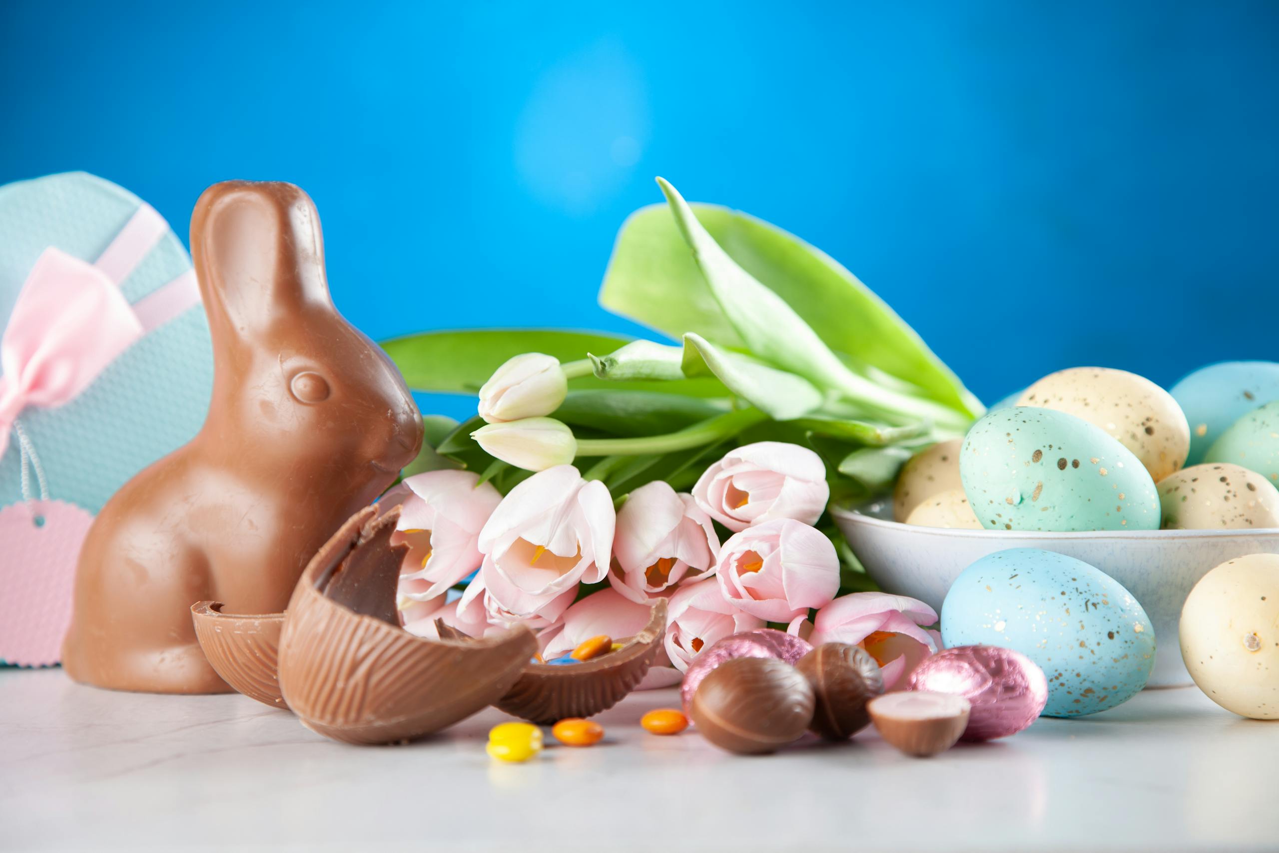 A vibrant Easter display featuring a chocolate bunny, pastel eggs, and tulips.