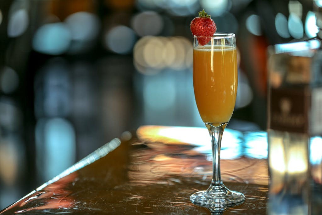 Elegant mimosa cocktail with a strawberry garnish in a champagne glass, perfect for celebrations.